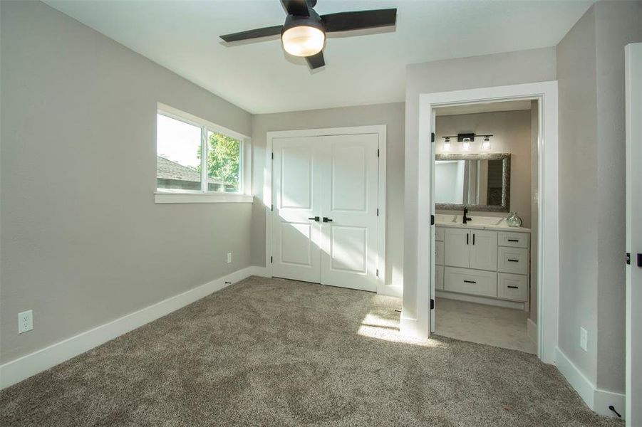 Unfurnished bedroom featuring ensuite bath, light carpet, sink, a closet, and ceiling fan