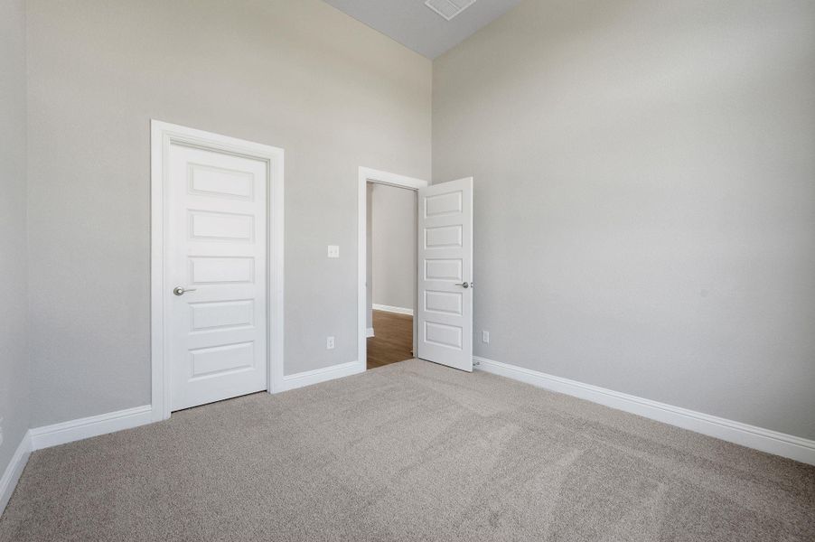 Unfurnished bedroom with carpet and a towering ceiling
