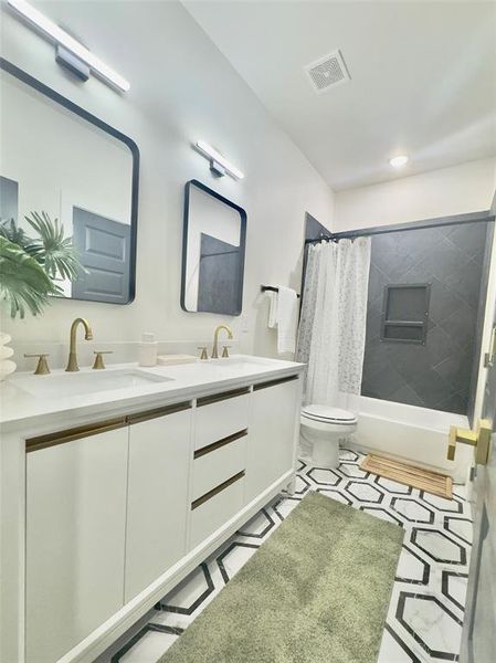 Full bathroom featuring tile flooring, shower / bath combination with curtain, toilet, and dual bowl vanity