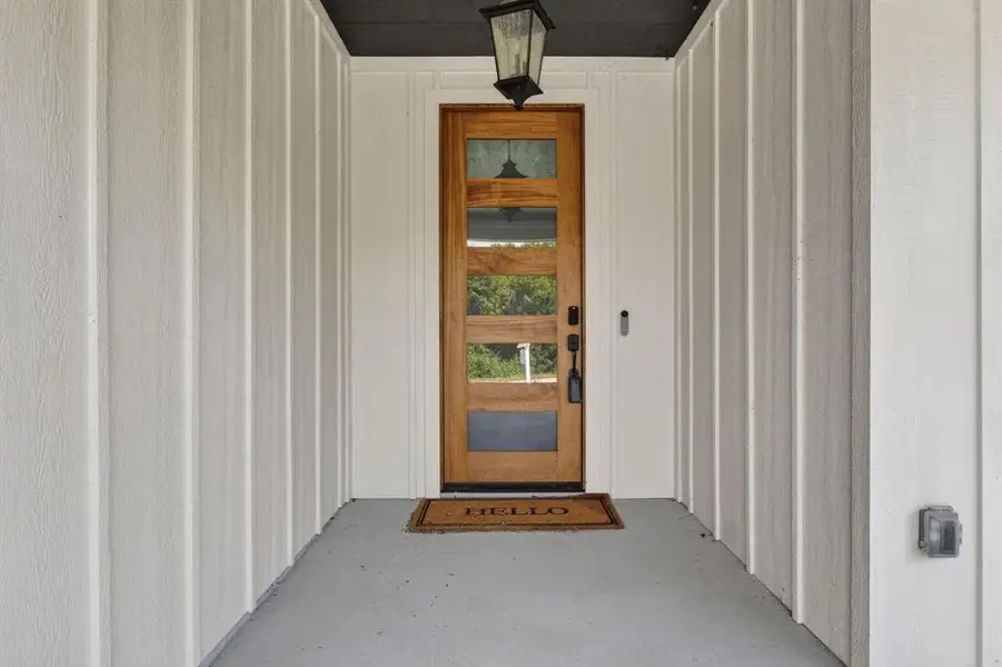 Wooden front door and oversized covered front porch area for homeowners to enjoy.