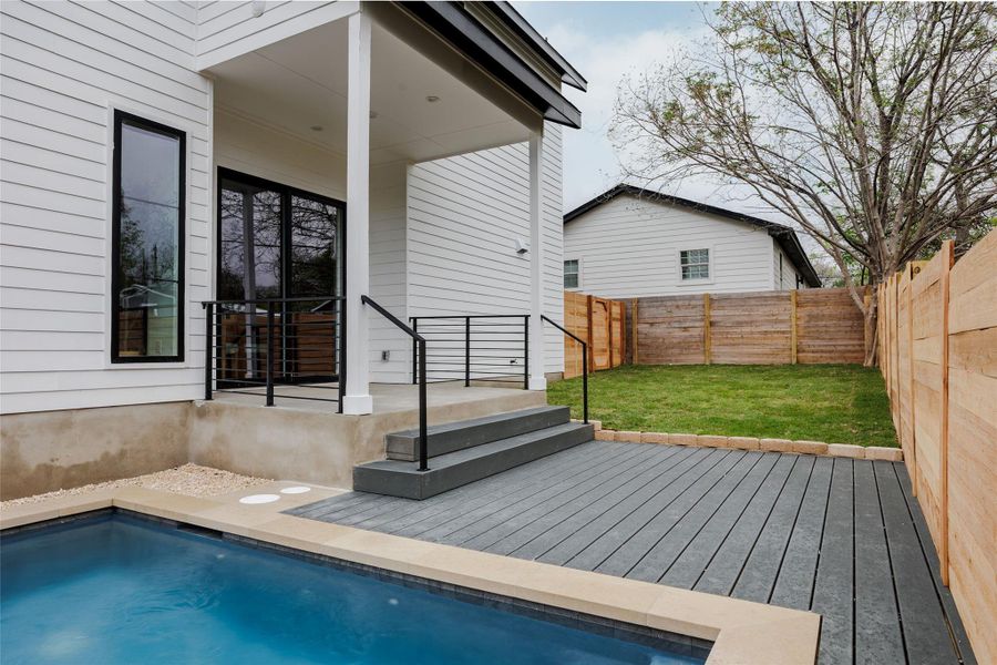 View of pool featuring a fenced backyard, a wooden deck, and patio surround
