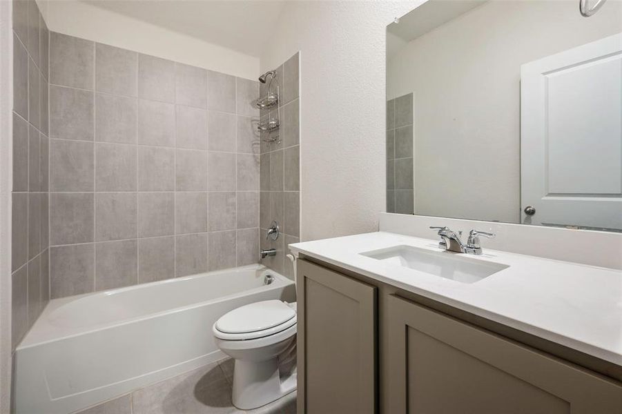 Full bathroom with tile patterned flooring, toilet, tiled shower / bath combo, and vanity