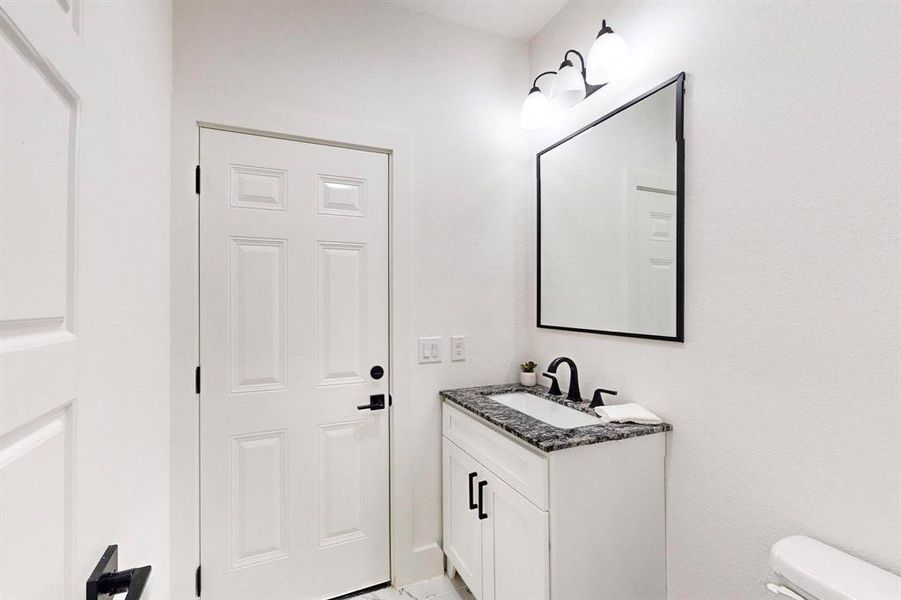 Bathroom with vanity and toilet with door leading outside