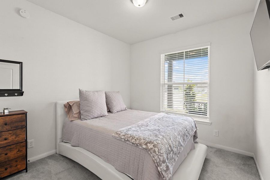 Nestled away quietly at the front of the home is the final secondary bedroom, featuring plush carpet, bright natural light, and peaceful view of the front porch.