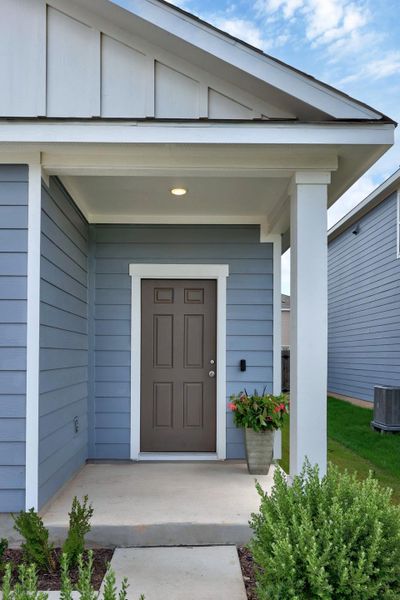 Inviting entryway featuring a covered porch, blue horizontal siding, a paneled brown door, and white trim