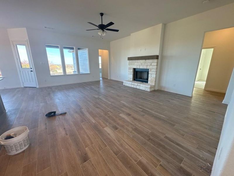 Unfurnished living room with a fireplace with raised hearth, dark wood finished floors, and ceiling fan Unfurnished living room with a fireplace with raised hearth, dark wood finished floors, and ceiling fan