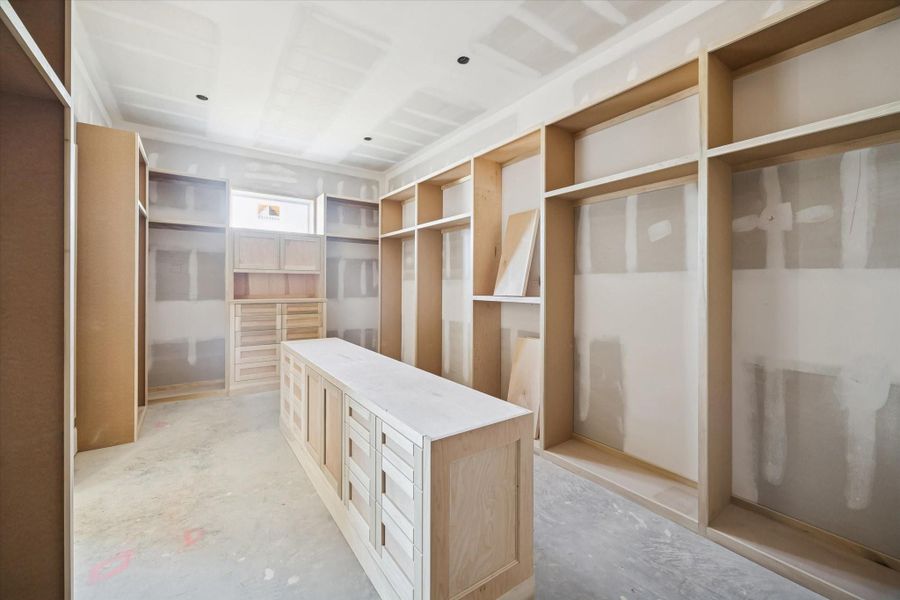 The primary closet features a large center island, extensive hanging space, and floor-to-ceiling cabinetry. The layout is designed to deliver boutique-style organization and everyday convenience. A true luxury amenity within the primary suite.