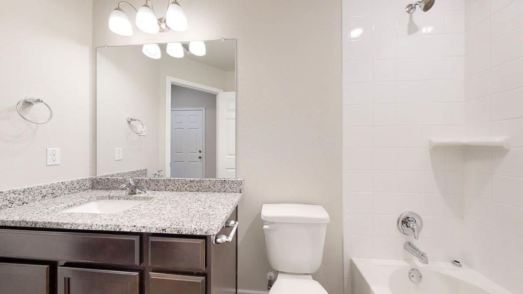 Bathroom featuring a dark wood-finish vanity with a granite countertop, undermount sink, and chrome fixtures