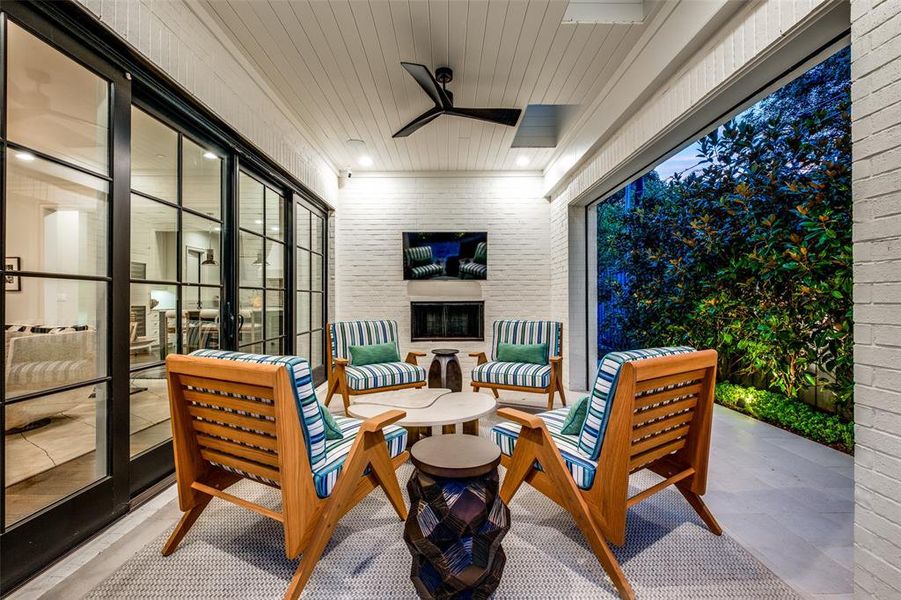 Loggia/outdoor living area with a fireplace and automated screens