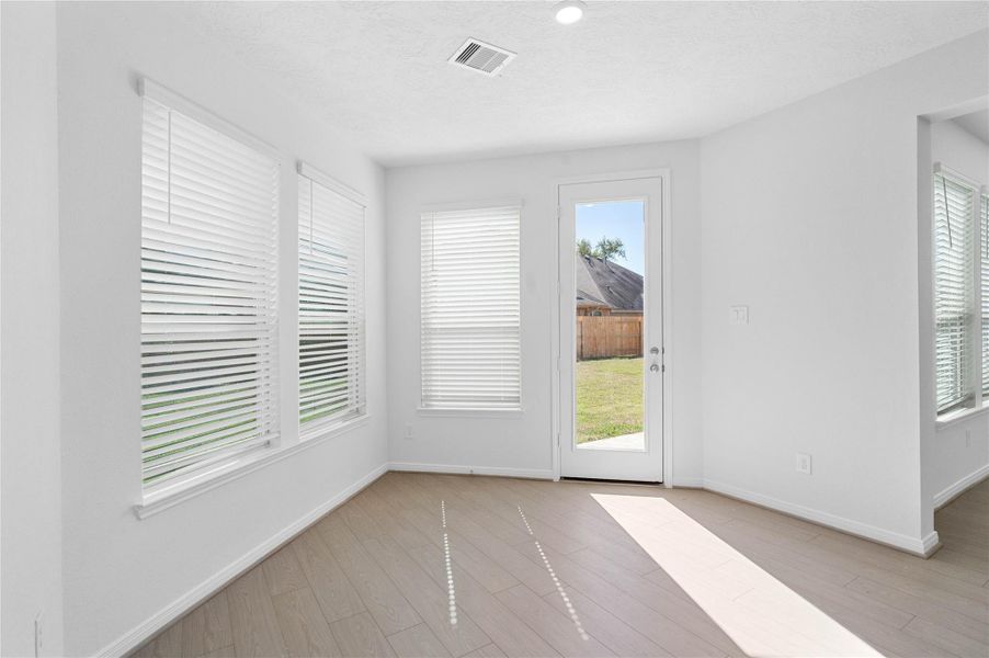 Start your day with a warm cup of coffee and quality time in this charming breakfast nook! Highlights include large windows with blinds, custom neutral paint, vinyl plank flooring, recessed lighting, high ceilings, and a convenient door leading to the rear patio slab and backyard.