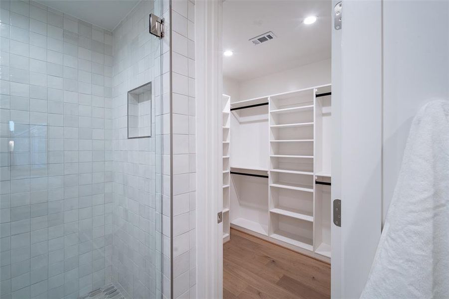 Spacious walk-in closet featuring light hardwood floors