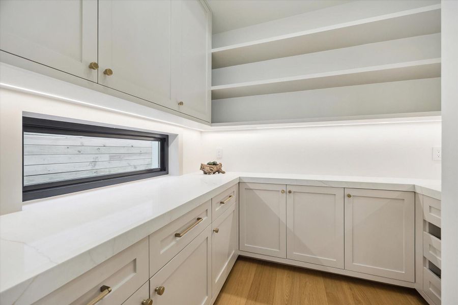 Walk-in pantry with custom shelving, ample storage from floor to ceiling, and quartz counters. Walk-in pantry with custom shelving, ample storage from floor to ceiling, and quartz counters.