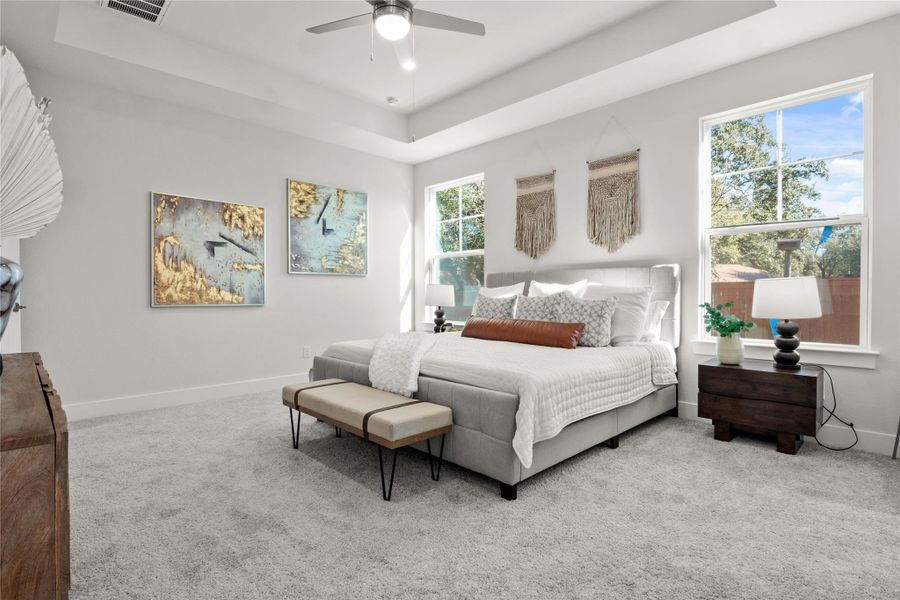Carpeted bedroom with a tray ceiling and ceiling fan Carpeted bedroom with a tray ceiling and ceiling fan