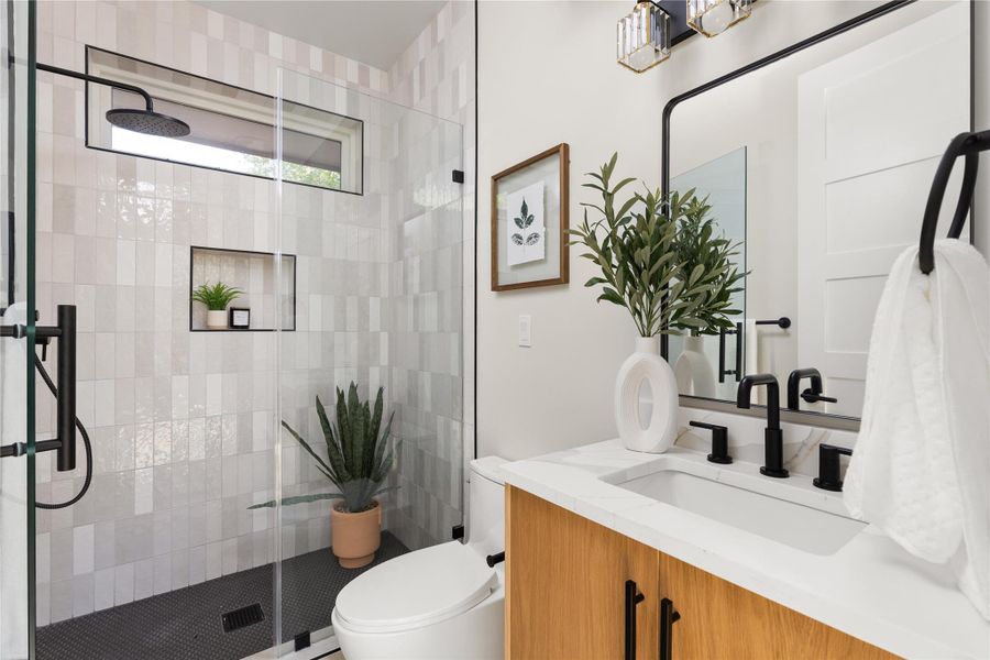 A glass-enclosed walk-in shower with vertical tile detailing highlights this modern bathroom.