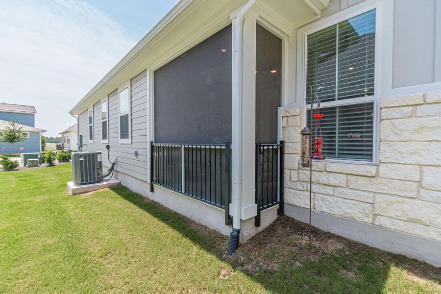 View of home's exterior featuring central AC, a yard, and stone siding