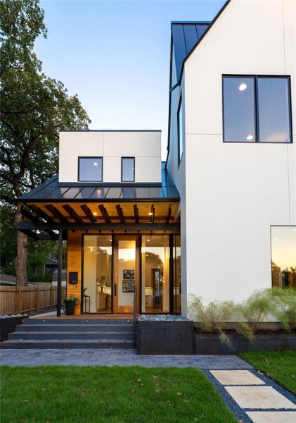 Rear view of house featuring a standing seam roof and stucco siding