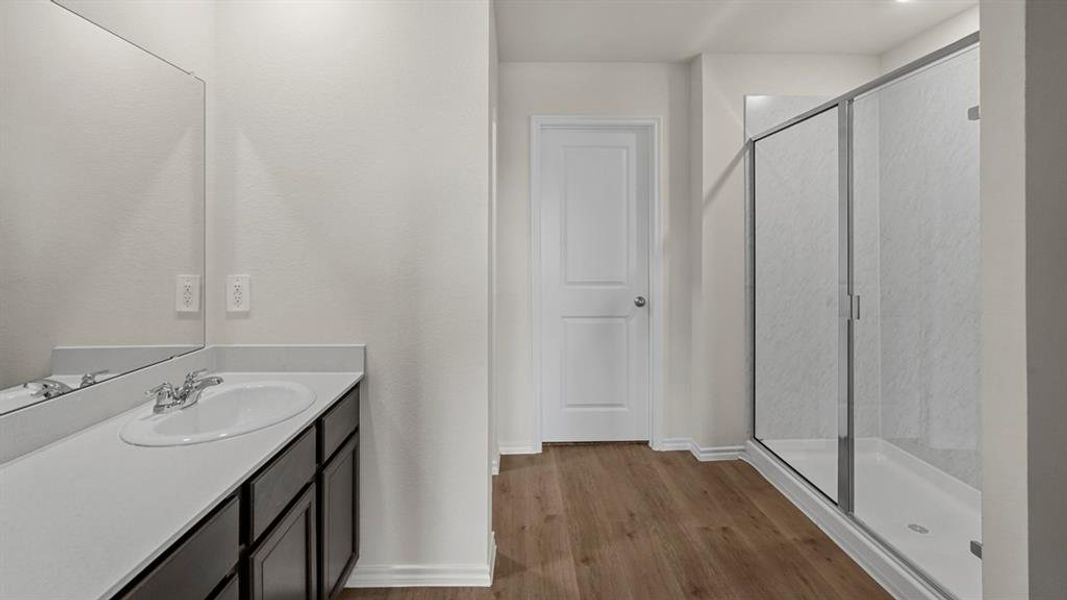 Bathroom featuring a single vanity with an integrated sink, dark wood-finish cabinetry, and a framed mirror