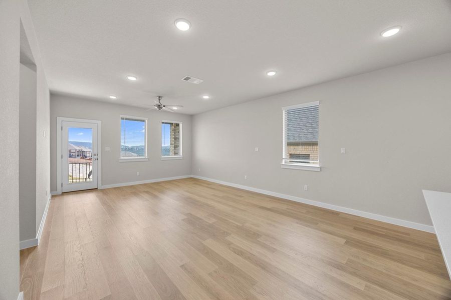 A generously proportioned living area boasts light wood flooring and plentiful natural light from multiple windows. A generously proportioned living area boasts light wood flooring and plentiful natural light from multiple windows.