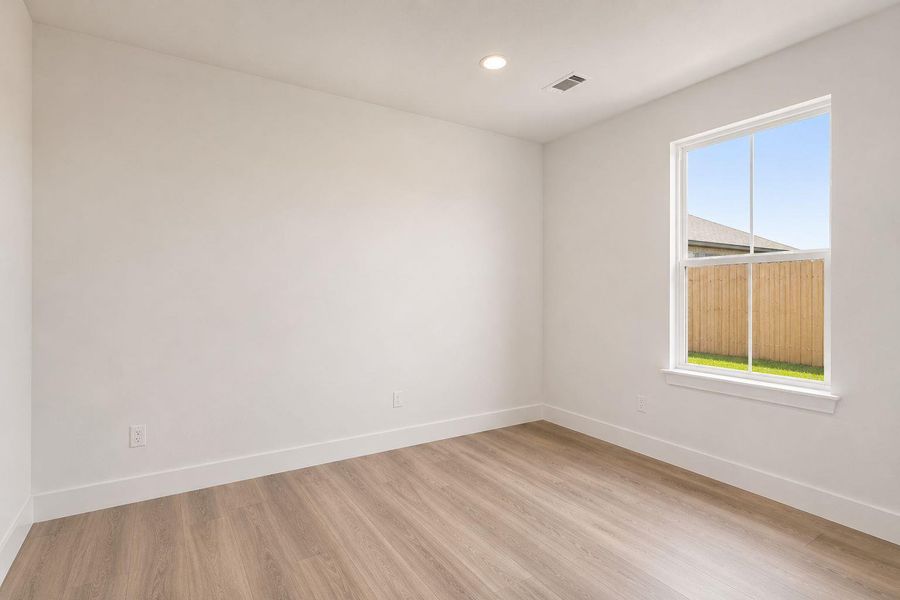 4th bedroom A well-lit room with resilient plank flooring and a clear view to the fenced yard.