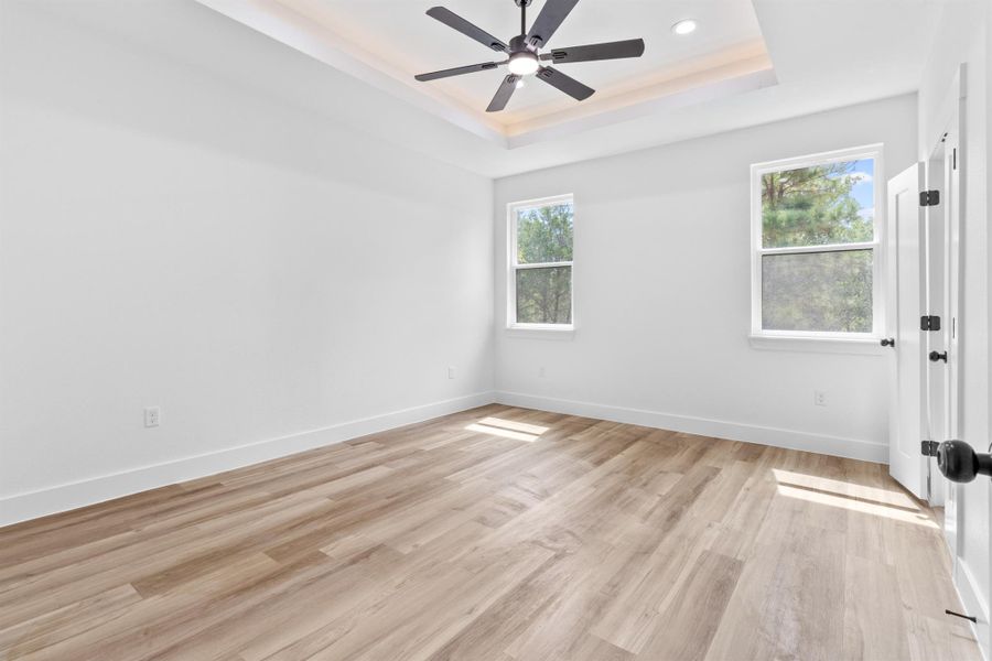 Unfurnished room featuring light wood finished floors, a raised ceiling, recessed lighting, and a ceiling fan
