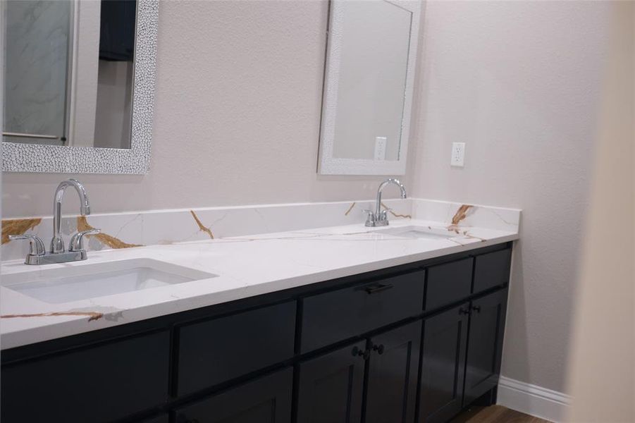 Bathroom with double vanity, wood finished floors, and a textured wall Bathroom with double vanity, wood finished floors, and a textured wall