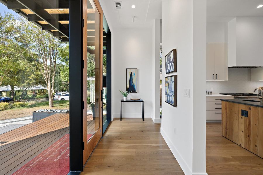 Hallway with light wood finished floors and recessed lighting