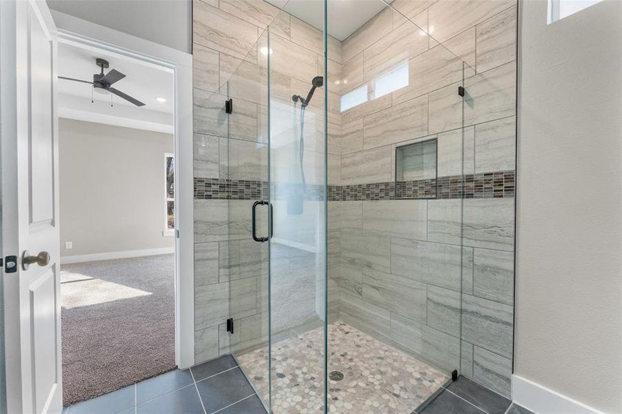 Bathroom with a shower with door, tile patterned floors, and ceiling fan