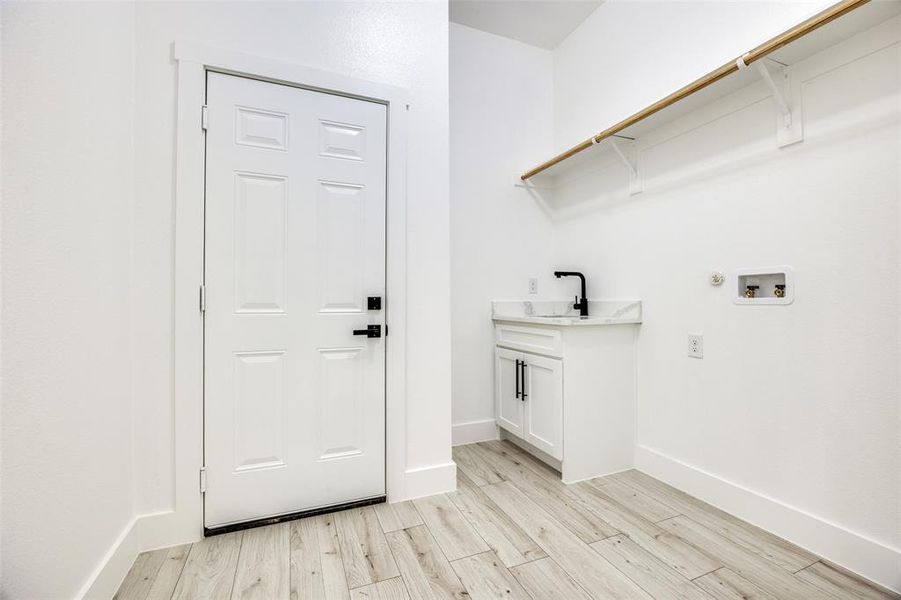 Laundry area featuring light wood finished floors, hookup for a washing machine, gas dryer hookup, and cabinet space Laundry area featuring light wood finished floors, hookup for a washing machine, gas dryer hookup, and cabinet space