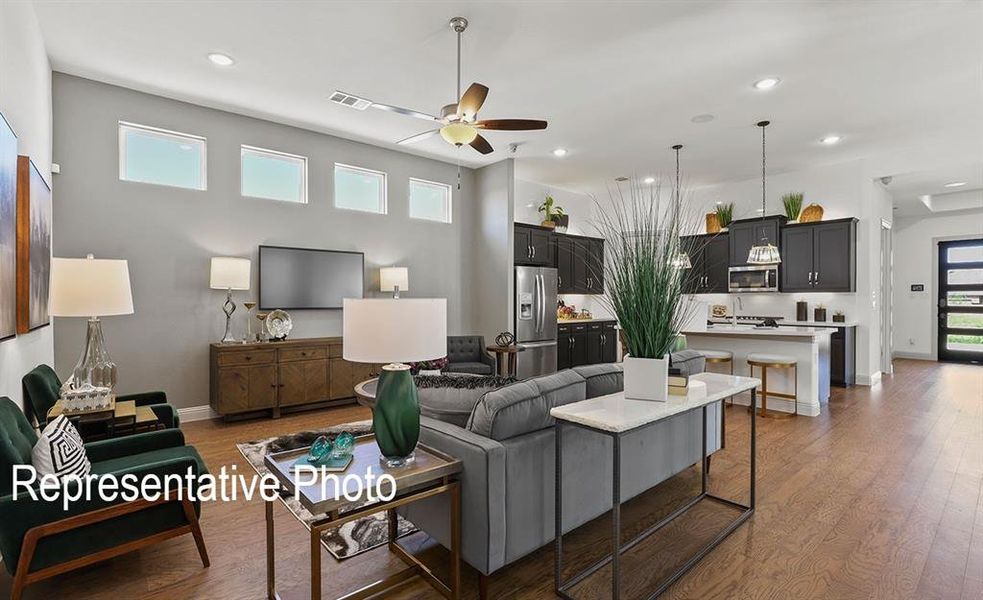Open-concept living space featuring wood-finish flooring, high ceilings, and recessed lighting Open-concept living space featuring wood-finish flooring, high ceilings, and recessed lighting