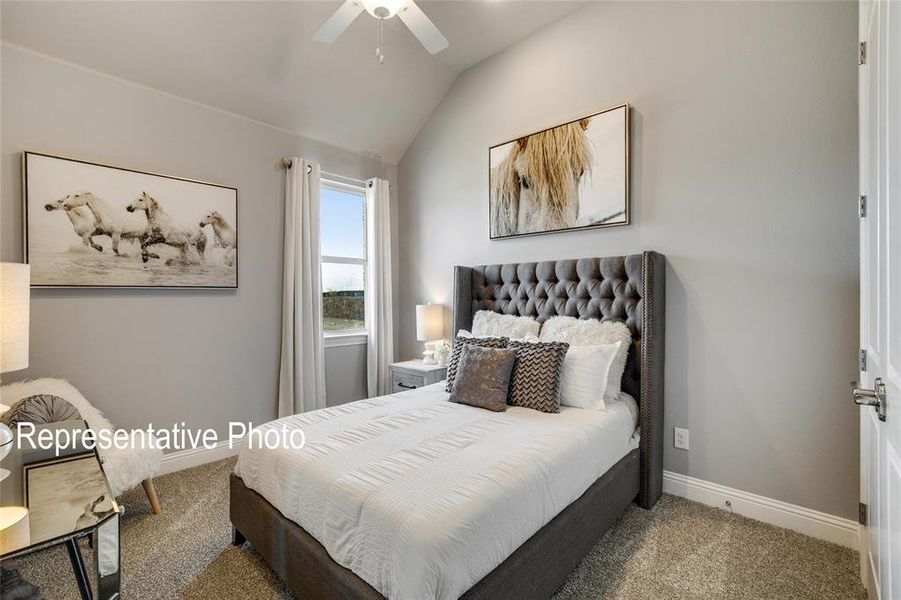 Carpeted bedroom featuring vaulted ceiling and ceiling fan