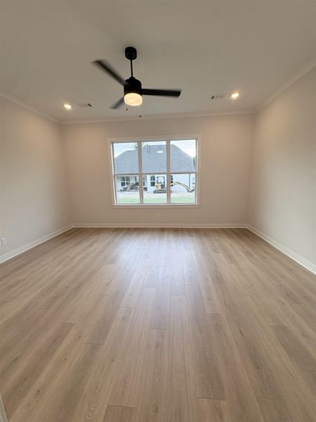 Recessed ceiling lighting, crown molding, a ceiling fan with light, wood-finish flooring, and a large window Recessed ceiling lighting, crown molding, a ceiling fan with light, wood-finish flooring, and a large window
