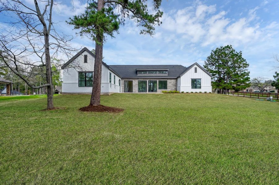 Expansive backyard view highlighting the home’s impressive architecture and the generous 1+ acre lot.