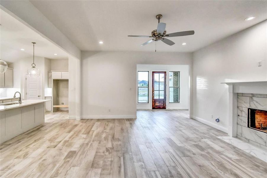 Unfurnished living room with light wood-type flooring, ceiling fan, a fireplace, and sink