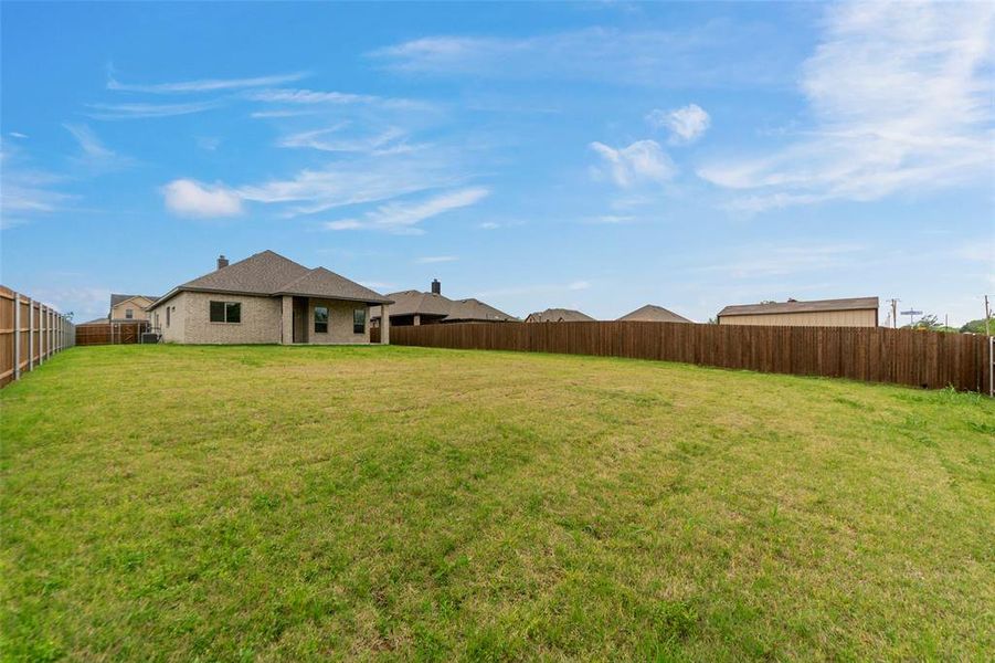 Expansive grassy lawn with a full privacy fence encompassing the perimeter
