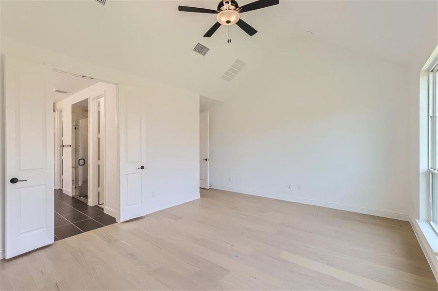 Unfurnished bedroom with multiple windows, wood-type flooring, ceiling fan, and vaulted ceiling