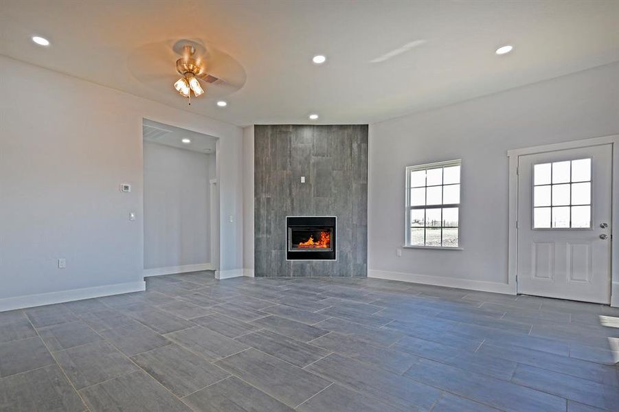 Unfurnished living room featuring recessed lighting, a tiled fireplace, a ceiling fan, and wood finish floors Unfurnished living room featuring recessed lighting, a tiled fireplace, a ceiling fan, and wood finish floors