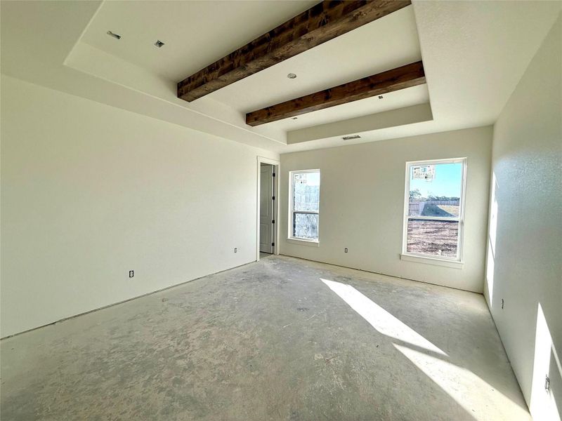 Spare room featuring beamed ceiling and concrete flooring Spare room featuring beamed ceiling and concrete flooring