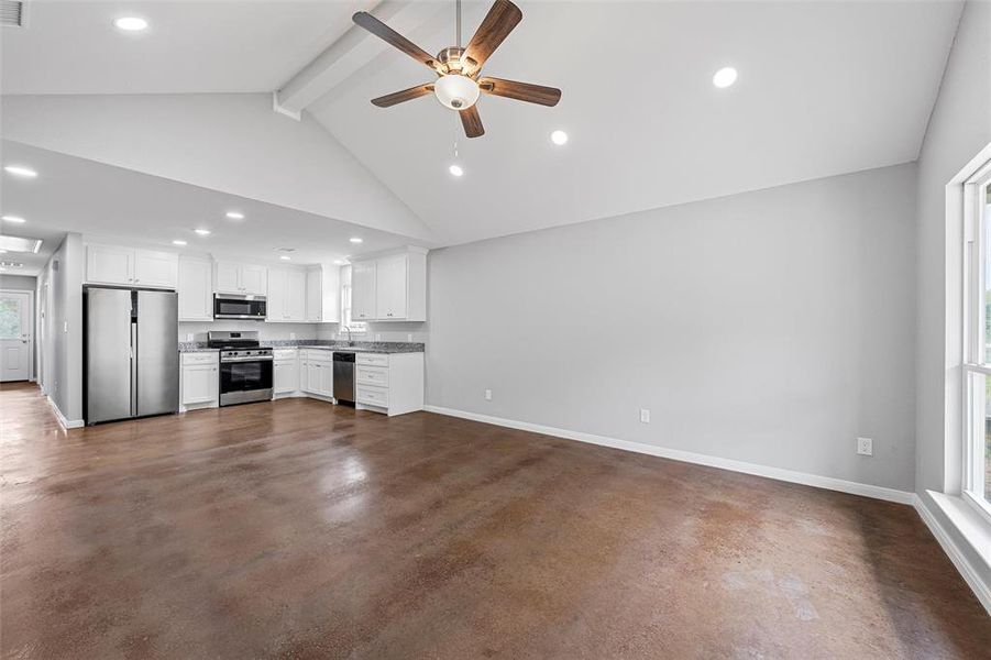 Unfurnished living room with baseboards, beamed ceiling, ceiling fan, and concrete floors