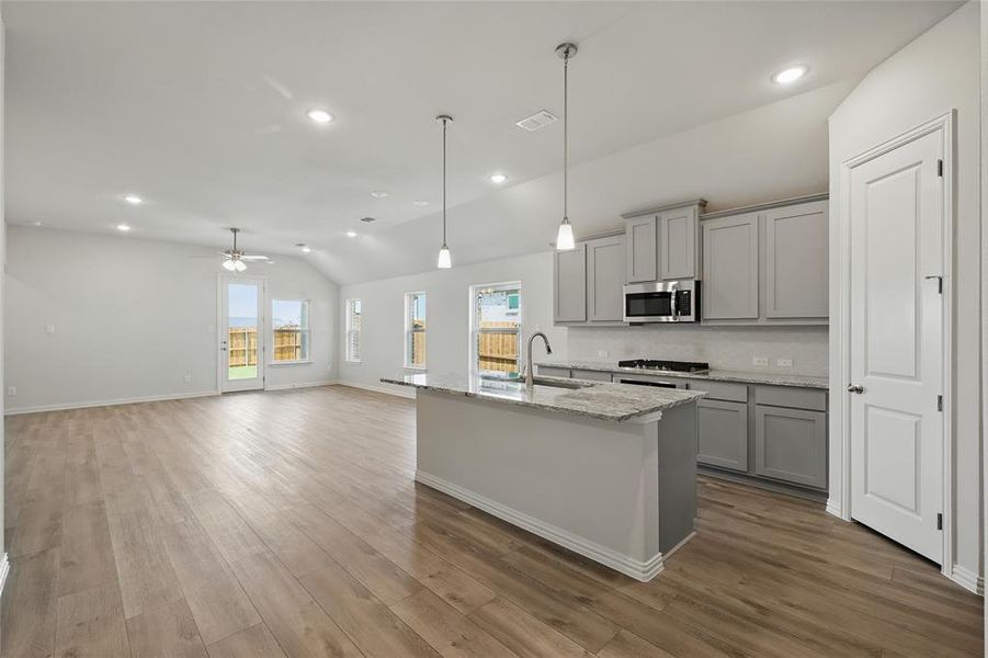 Kitchen with appliances with stainless steel finishes, gray cabinets, vaulted ceiling, a sink, and healthy amount of natural light Kitchen with appliances with stainless steel finishes, gray cabinets, vaulted ceiling, a sink, and healthy amount of natural light