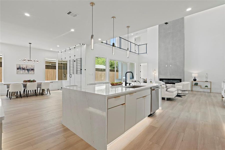 Kitchen featuring a chandelier, open floor plan, a large fireplace, dishwasher, and light wood-style flooring