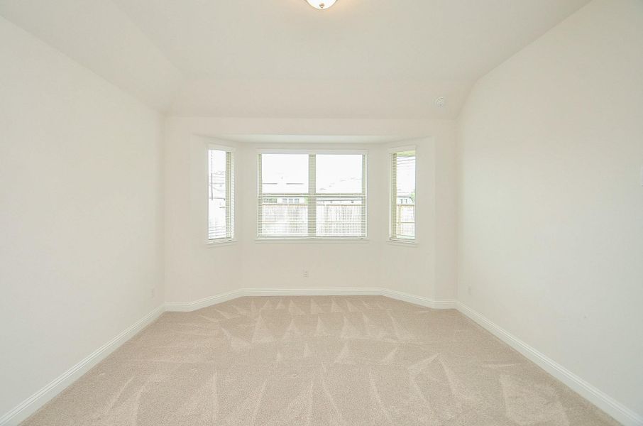 This bright, spacious room features a bay window that allows plenty of natural light, with clean white walls and plush carpet flooring, creating a cozy and inviting atmosphere.