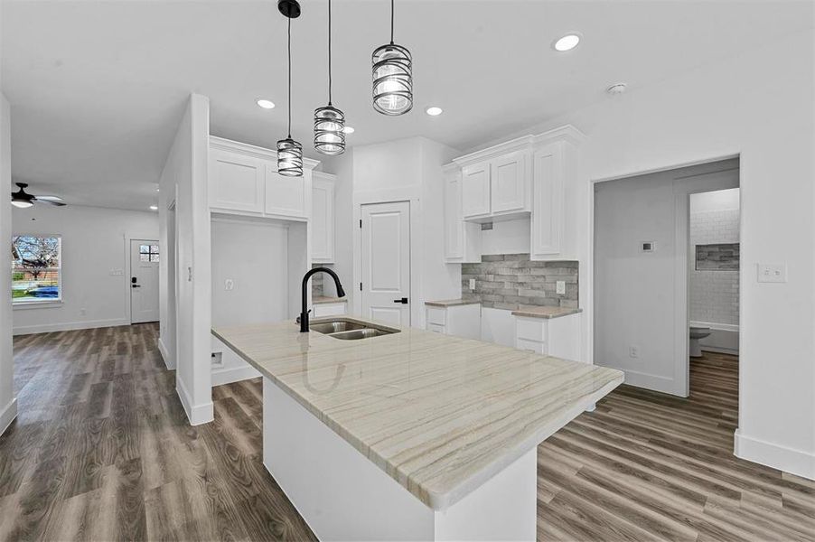 Kitchen featuring white cabinets, ceiling fan, sink, and a kitchen island with sink