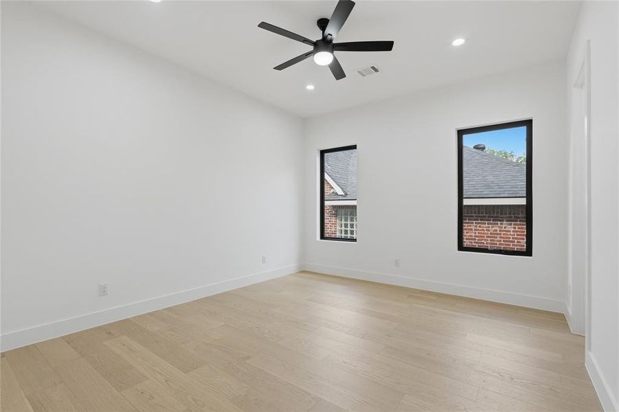 Spacious room featuring white walls, light wood-finish flooring, and a ceiling fan with integrated lighting Spacious room featuring white walls, light wood-finish flooring, and a ceiling fan with integrated lighting