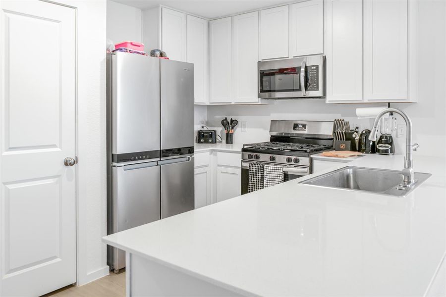 Modern kitchen with sleek stainless steel appliances, white cabinetry, and a spacious countertop with an integrated sink. Ideal for home cooking and entertaining.