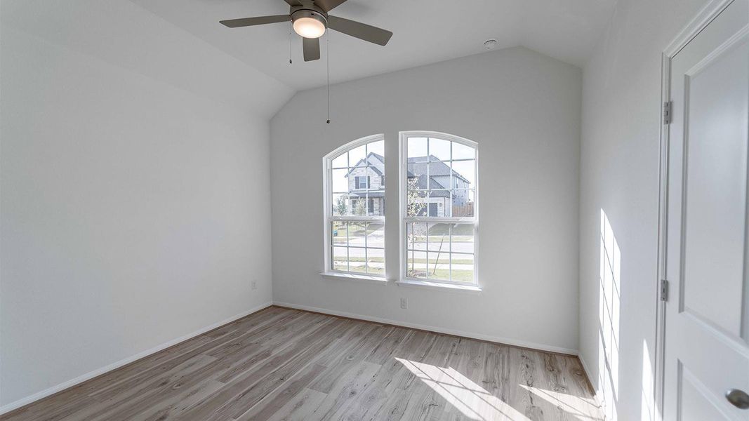 Unfurnished room with a ceiling fan, vaulted ceiling, and light wood-style flooring