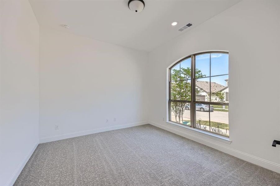 Arch-top window providing natural light, complemented by neutral-toned carpeting, white walls, and recessed lighting Arch-top window providing natural light, complemented by neutral-toned carpeting, white walls, and recessed lighting