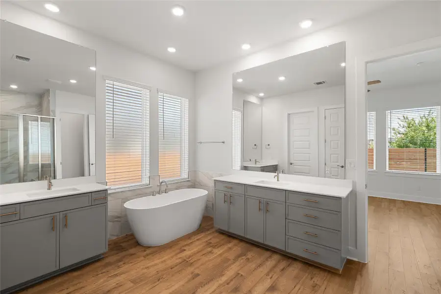 A well-appointed primary bath features dual vanities, a luxurious soaking tub, and a spacious glass-enclosed shower. A well-appointed primary bath features dual vanities, a luxurious soaking tub, and a spacious glass-enclosed shower.