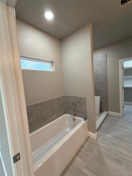 Full bath featuring a bath, wood finished floors, and a walk in shower Full bath featuring a bath, wood finished floors, and a walk in shower