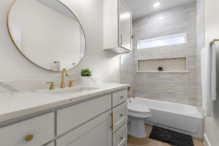 Full bathroom featuring tiled shower / bath combo, vanity, wood-type flooring, and toilet