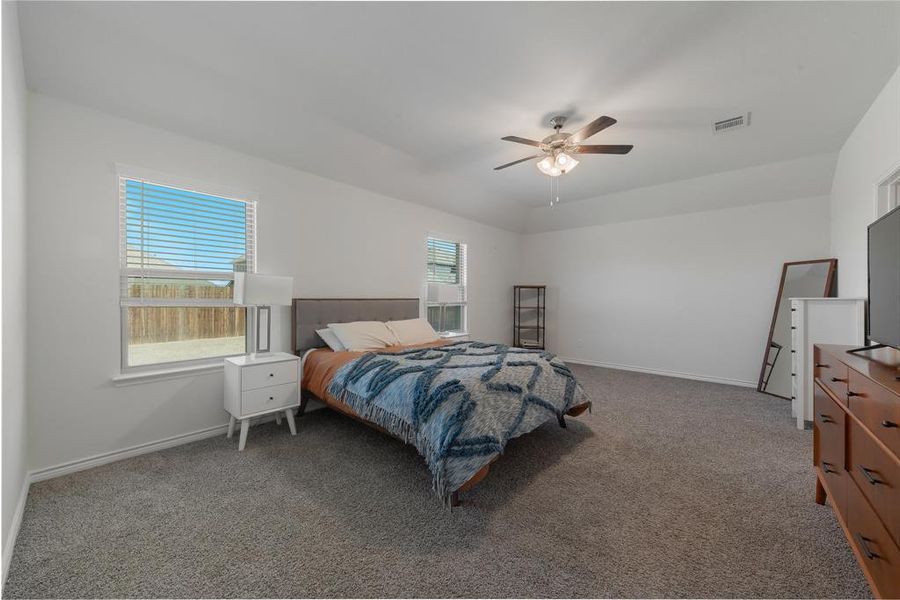 Carpeted bedroom featuring a ceiling fan, visible vents, and baseboards